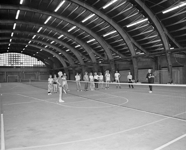 882636 Afbeelding van een tennisles die gegeven wordt in de oude veilinghal voor Groenten- en Vruchtenveilingen ...